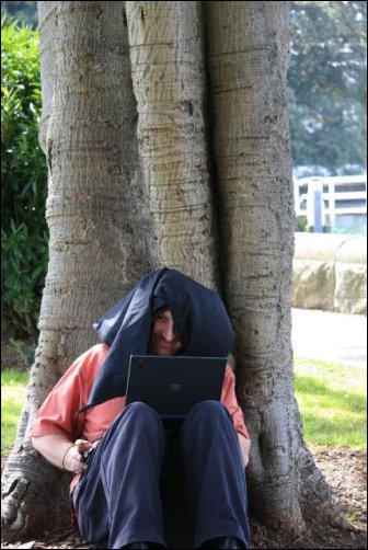 Steven Siewert under a black cloth looking at multimedia on his laptop